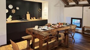 Une cuisine rustique avec une table et un banc en bois, des meubles noirs et un plafond en pente avec des poutres apparentes.