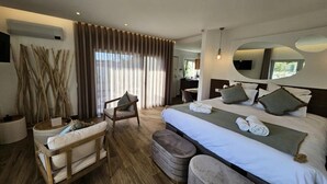 A hotel room with a large bed, a chair, a small table, and a mirror. - Rainbow Apartments in Marinha Grande (Marinha Grande)