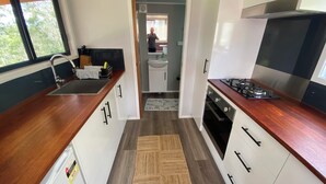 Uma cozinha compacta com bancadas de madeira, fogão embutido e armários brancos.