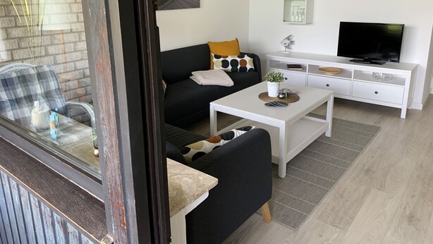 A modern living room with a sofa, coffee table, TV, and decorative items. - Apartment "Halvar" with Balcony and WiFi (Maasholm)
