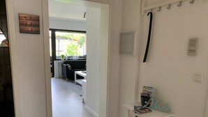 A hallway leading to a living area with a sofa, a small table, and a window with a view of the outdoors. - Apartment "Halvar" with Balcony and WiFi (Maasholm)