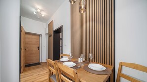 A dining area with a wooden table set for four, including plates, cutlery, and glasses. - Apartment at Linden Square - Trutnov (Trutnov)