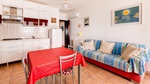 A compact living space with a kitchenette, a dining area, and a sofa. - With beachfront terrace and air conditioning (Castelsardo)