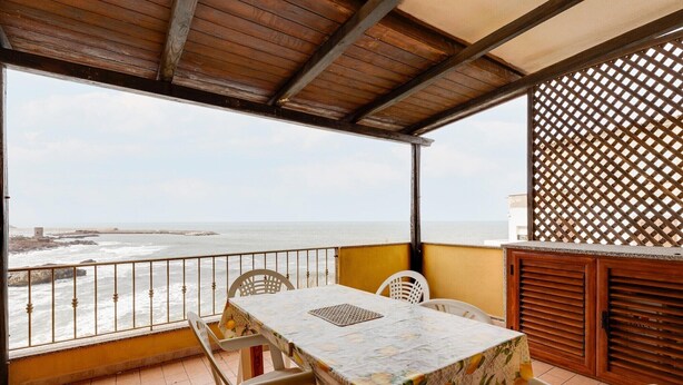 A balcony with a table and chairs, overlooking the sea. - With beachfront terrace and air conditioning (Castelsardo)