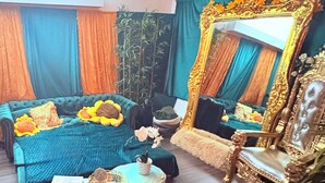 Ein Zimmer mit einem großen Bett, einem Sessel, einem kleinen Tisch und einem Spiegel.