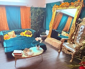 Ein Zimmer mit einem großen Bett, einem Sessel, einem kleinen Tisch und einem Spiegel.