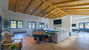 A spacious living area with a herringbone wood floor, a stone fireplace, and a large kitchen area. - Sleeps 20 | Two 4BR Homes | Resort Pool + Hot Tub + Firepit | Summerwell (Thermal)
