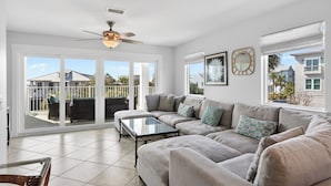 A spacious living room with a large sectional sofa, a glass coffee table, and a ceiling fan. - Exclusive Beach Access + Private Pool + Sunset Views | Sandy Pelican (Seacrest)