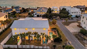 A residential area with houses, a swimming pool, and a view of the ocean at sunset. - Exclusive Beach Access + Private Pool + Sunset Views | Sandy Pelican (Seacrest)