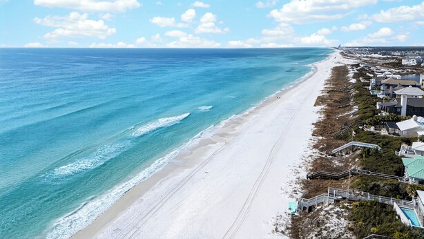 A coastal view with a beach, ocean, and beachfront properties. - Exclusive Beach Access + Private Pool + Sunset Views | Sandy Pelican (Seacrest)