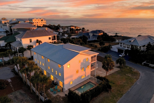 Aerial sunset over the beachside neighborhood—Gulf views, palm-lined streets, and that golden-hour glow.