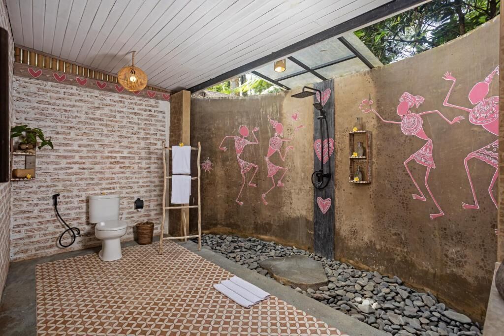 Une salle de bain avec un mur en briques au style rustique, des toilettes blanches, une douche et un carrelage à motifs.