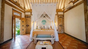 A room with a bed under a canopy, a bench, and a small table with a magazine. - Sacred Jewel by GenuineHost (Payangan)