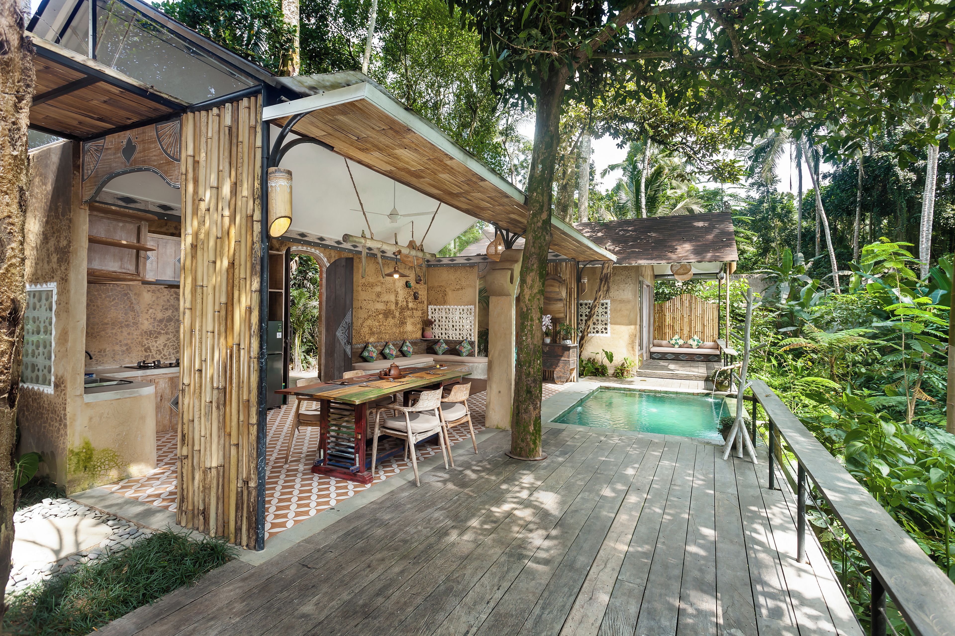 A wooden deck with a pool, surrounded by lush greenery.