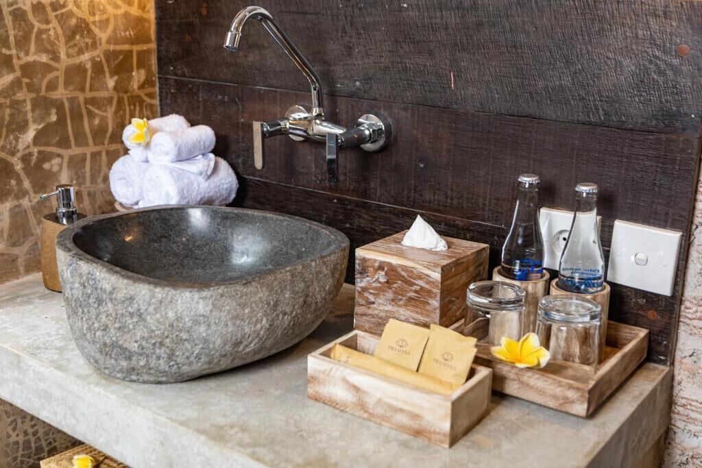 A stone sink with a modern faucet, a towel rack with folded towels, and a wooden box with toiletries.
