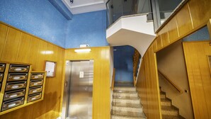 A modern interior with a wooden staircase, a metal elevator, and a blue wall. - HomeHolidaysRentals Coquette - Costa Barcelona (Pineda de Mar)