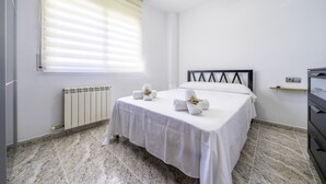 A clean, modern bedroom with a bed, a ceiling fan, a radiator, and a window with blinds. - HomeHolidaysRentals Coquette - Costa Barcelona (Pineda de Mar)