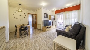 A living room with a sofa, TV, and dining area. - HomeHolidaysRentals Coquette - Costa Barcelona (Pineda de Mar)