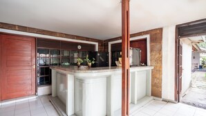 A kitchen with a central island, a red door, and a window with blinds. - rehat at hotel kurnia karapitan (Bandung)