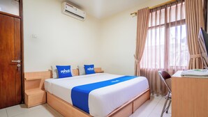 A hotel room with a wooden bed, a desk, and a chair. - rehat at hotel kurnia karapitan (Bandung)