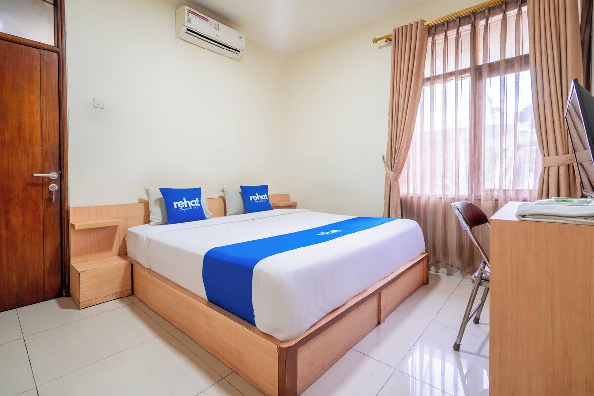 Une chambre d’hôtel avec un lit en bois, un bureau et une chaise.