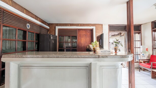 A kitchen with a large island, wooden cabinets, and a reception area with a water dispenser. - rehat at hotel kurnia karapitan (Bandung)