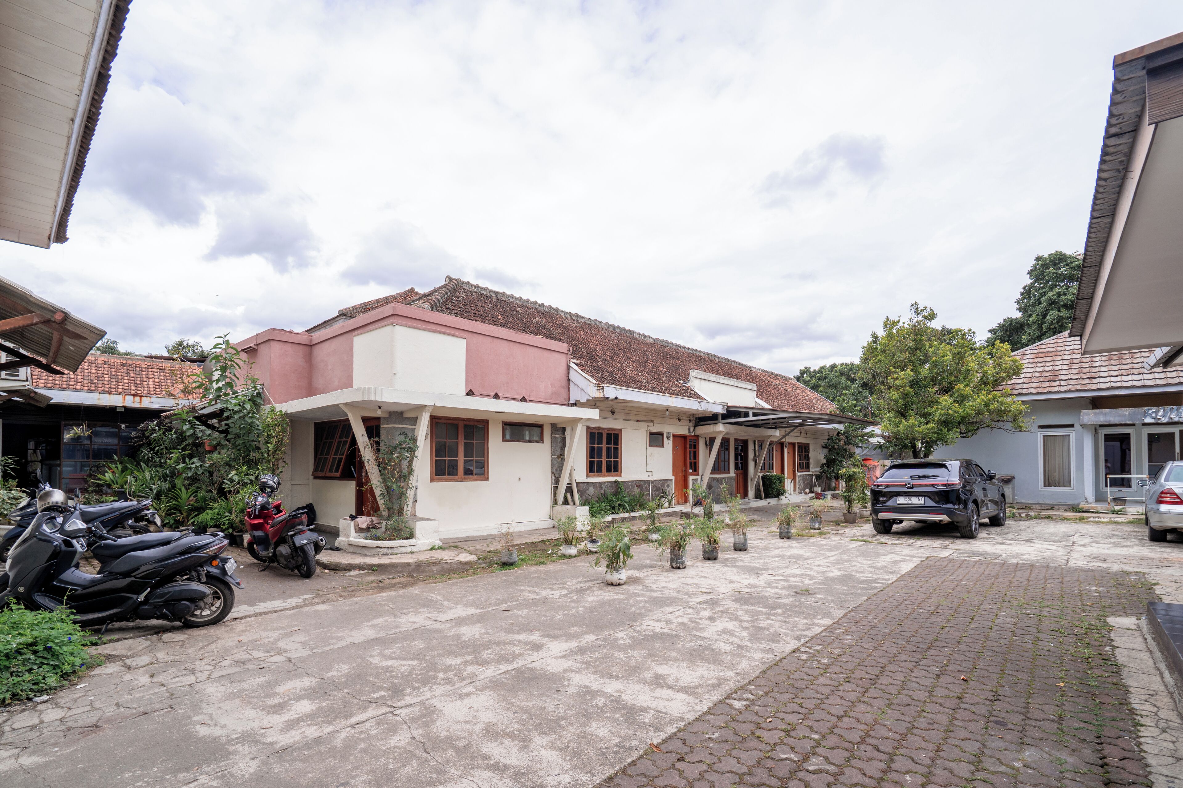A residential street with houses, parked motorcycles, and a car.