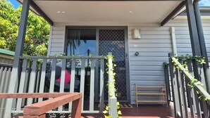 A covered porch with a bench, a door with a security screen, and a small table.