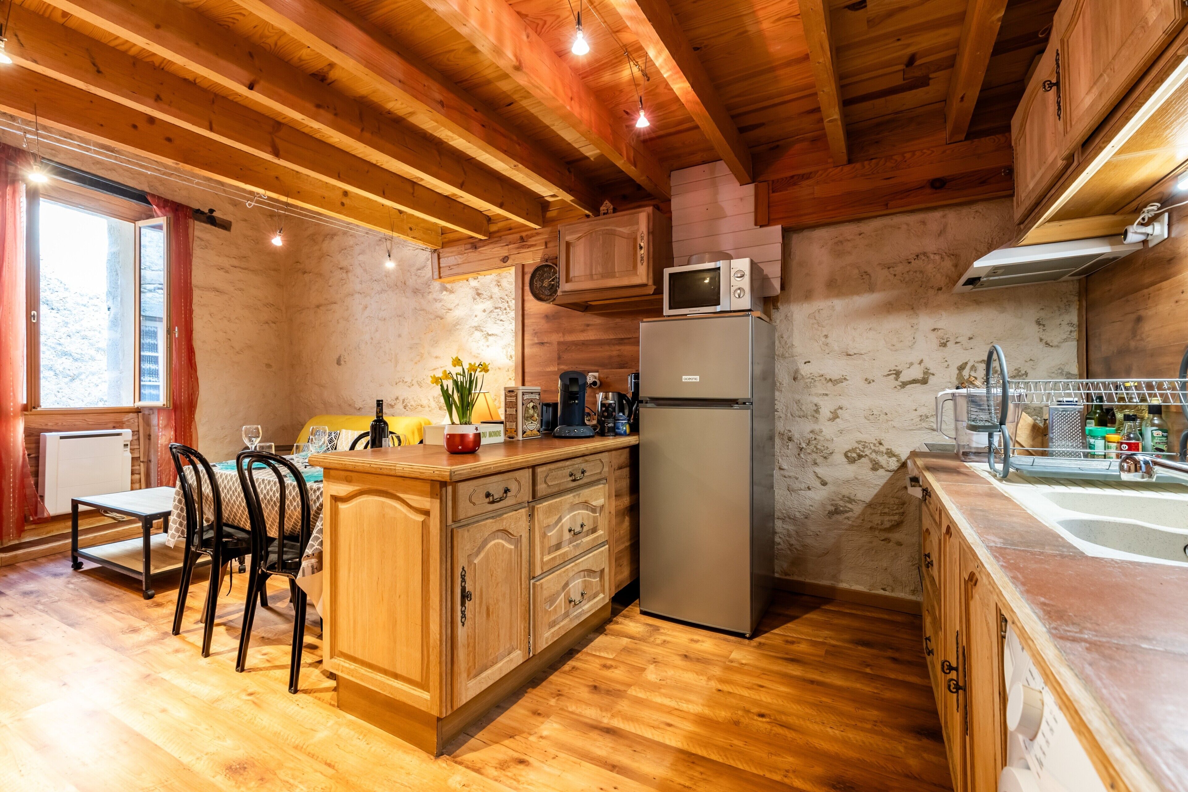 Un interior de madera con área de cocina que incluye un refrigerador, microondas y armarios de madera.