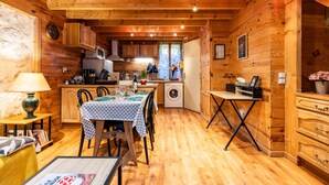 A cozy wooden cabin interior with a dining area, kitchen, and a small table with a lamp. - Saint François Apartment – Romantic Getaway (Monségur)