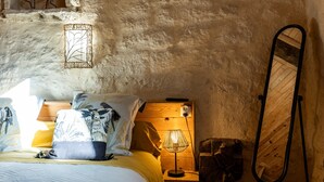 A bedroom with a bed, bedside lamp, and a mirror on the wall. - Saint François Apartment – Romantic Getaway (Monségur)