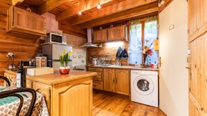 A wooden cabin interior with a kitchen, a washing machine, and a dining area. - Saint François Apartment – Romantic Getaway (Monségur)