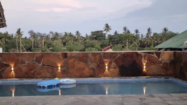 Une piscine avec des murs en pierre et un éclairage intégré.