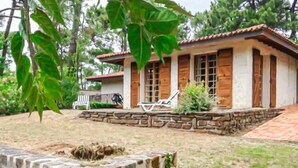 A two-story house with a stone foundation, a tiled roof, and wooden shutters. There are two lounge chairs on the porch. - Maison accès plage direct (Les Mathes)