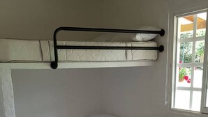 Een kamer met twee bedden, elk voorzien van een kussen en een opgevouwen handdoek. Er is een raam met uitzicht op groen.
