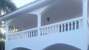 Ein zweistöckiges Gebäude mit weißer Fassade, einem befestigten Eingangsbereich und einem Auto auf der Auffahrt.