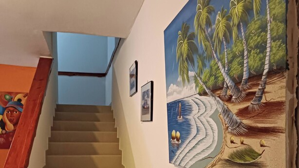 Eine Treppe mit einem hölzernen Geländer und einer Wand mit einem Wandbild vom tropischen Strand.