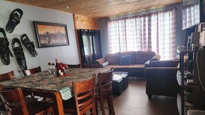 Un comedor con una mesa y sillas de madera, un sofá y un televisor al fondo.