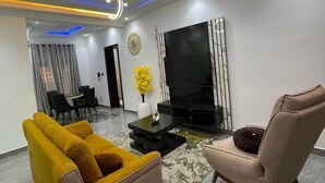 Un salon moderne avec un canapé, un fauteuil, une télévision et des éléments de décoration.
