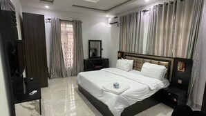 Une chambre moderne avec un grand lit, un bureau et une télévision.