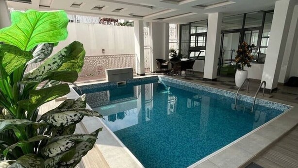 Une piscine intérieure moderne, dotée d’un sol carrelé et d’un plafond avec des spots encastrés.