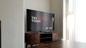 En tv-apparat står på ett träställ, och på skärmen visas Netflix-logotypen.