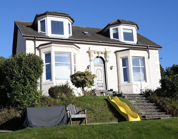 A two-story house with a bay window, a front door with a number '5', and a yellow slide. - Carmona Bank , Dunoon - sleeps 8 guests, dog friendly (DUNOON)