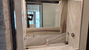 A bathroom with a marble sink, a handheld mirror, and a bottle of soap. - Waterfront Luxury Studio (Thessaloniki city)