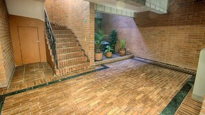 Eine Treppe mit Backsteinwänden, einem Metallgeländer, Blumentöpfen und einer Tür am unteren Ende.