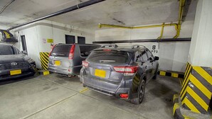 Eine Parkgarage mit drei Autos in markierten Stellplätzen, deren Bordsteine gelb und schwarz gestreift sind.