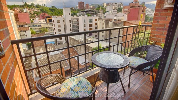 Ein Balkon mit Blick auf eine Stadtlandschaft, ausgestattet mit einem kleinen Tisch und zwei Stühlen.