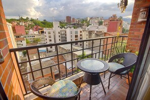 A balcony with a view of a cityscape, featuring a small table and two chairs. - Beautiful Apartment Cali River (Cali)