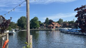 A riverside view with boats docked, a wooden post with a sign, and a clear blue sky. - Rural Norfolk Cottage welcoming 3 dogs (Hickling)