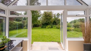 A conservatory with a view of a well-maintained garden. - Rural Norfolk Cottage welcoming 3 dogs (Hickling)